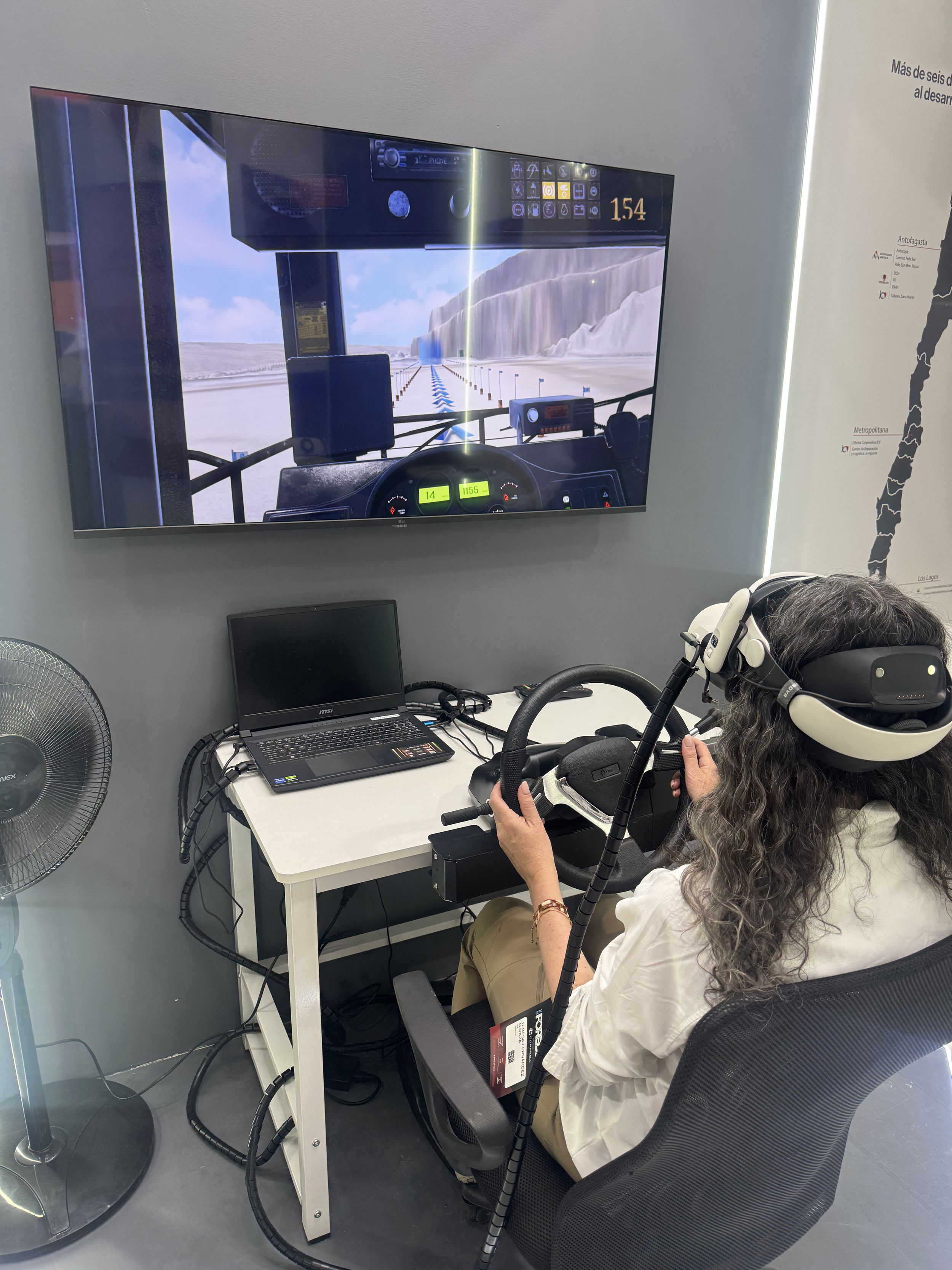Asistente a Expo FOREDE 2026 en un simulador de conducción con visor de realidad virtual y volante; la pantalla muestra la vista desde la cabina.