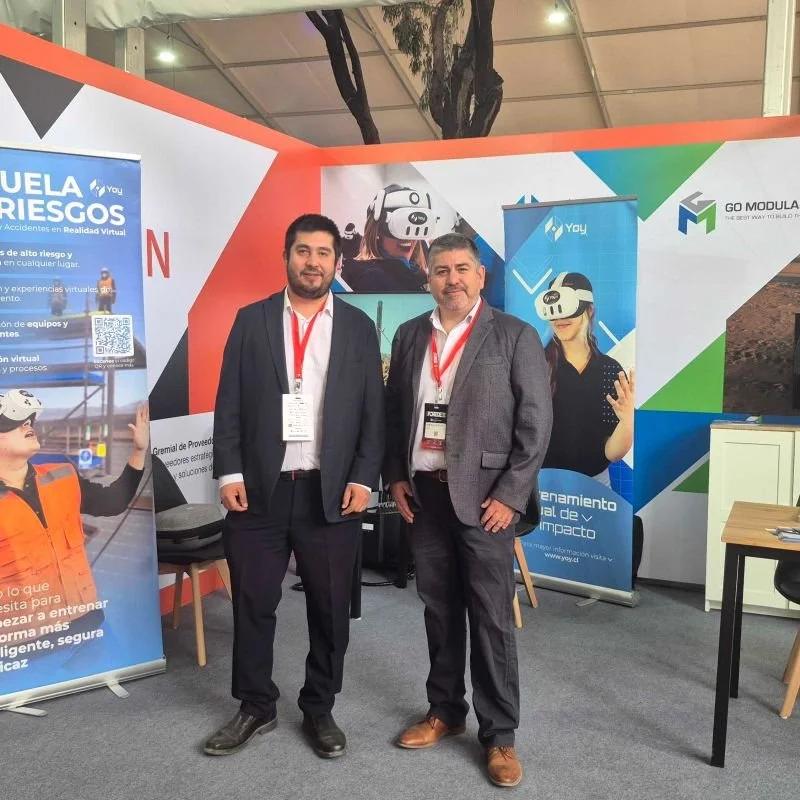 Dos integrantes del equipo de Yoy Simulators en su stand de Expo FOREDE 2026, frente a los paneles de capacitación en realidad virtual.